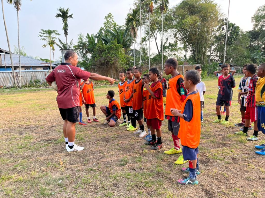 (Yahya Sosomar atau Coach Yaso memberikan arahan kepada anak-anak SSB All Star Nabire saat latihan sepak bola di lapangan SMP Negeri 3 Nabire. Melalui pembinaan sejak usia dini, mantan striker Persinab ini berupaya menanamkan disiplin dan mengembangkan bakat sepak bola generasi muda Papua)