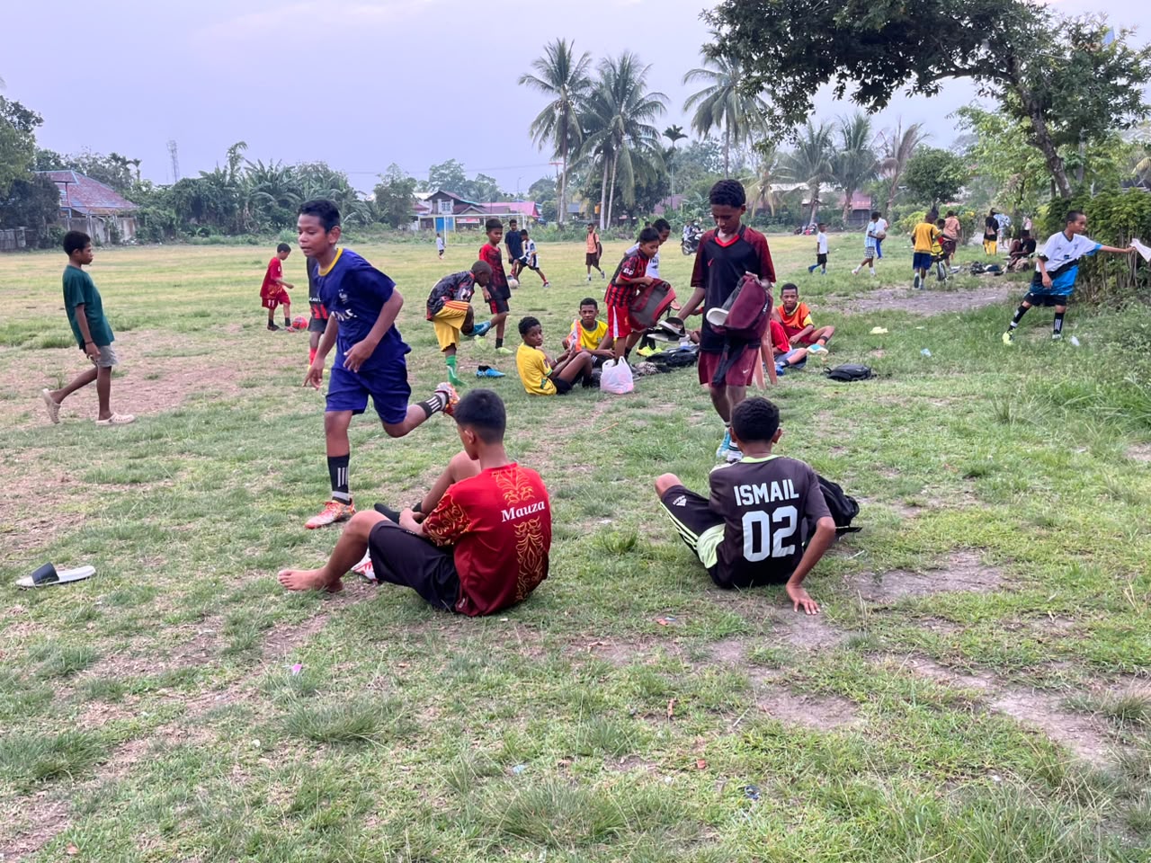 (Anak-anak SSB All Star Nabire berlatih dan beristirahat di pinggir lapangan sebelum melanjutkan aktivitas sepak bola. Di bawah bimbingan Coach Yaso, mereka terus mengasah kemampuan dengan harapan memperoleh kesempatan bertanding dan berkembang menjadi pemain yang lebih baik)